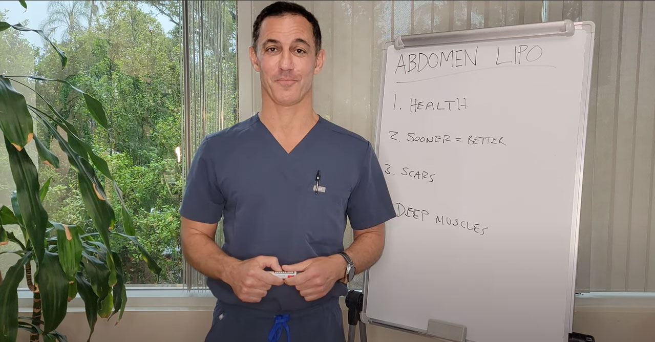 Dr. Tirgari in blue scrubs with a white board behind him
