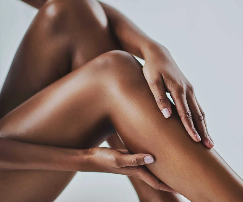 Closeup of a woman's hands on her leg.
