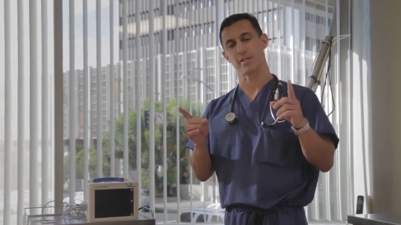 A healthcare professional in scrubs stands in an office with a stethoscope