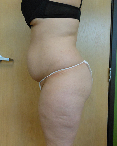 A person is shown in profile wearing a black bra and white thong against a wooden background