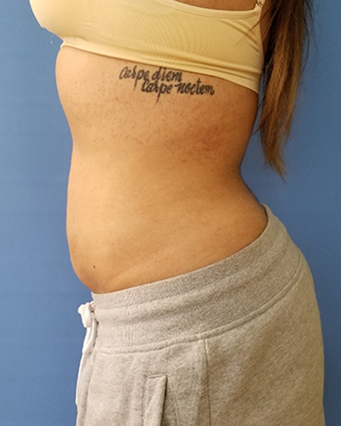 Profile view of a person wearing a crop top and sweatpants, with visible tattoo on side